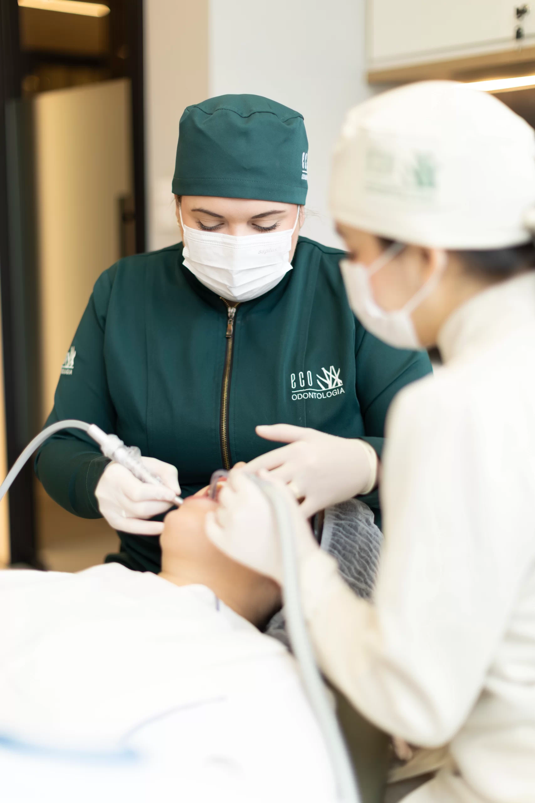 Em um ambiente de consulta acolhedor e profissional na clínica Eco Odontologia, uma dentista conversa de forma sorridente e empática com uma paciente. Ambas estão sentadas em uma moderna sala de atendimento clínico-geral, equipada com notebook para análise de casos e planejamento personalizado. A imagem destaca o foco da clínica no atendimento humanizado, na transparência do diálogo e no bem-estar do paciente, reforçando a excelência da Eco Odontologia em oferecer uma experiência odontológica segura, confortável e de alto padrão desde a primeira avaliação.