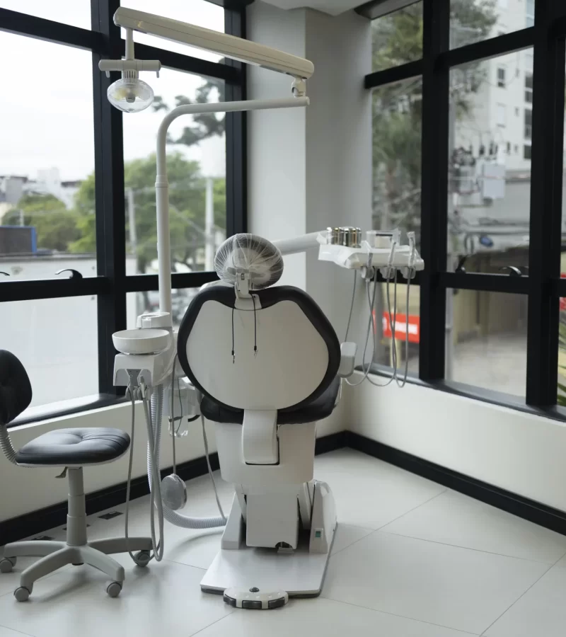 Vista de um consultório da clínica Eco Odontologia, equipado com uma cadeira odontológica de alta tecnologia e ergonomia, posicionada em um espaço amplo e iluminado com vista para a cidade. O ambiente clean e sofisticado foi planejado para oferecer uma experiência de tranquilidade e bem-estar, unindo uma infraestrutura de padrão internacional ao acolhimento necessário para que o paciente se sinta seguro e confortável durante todo o seu atendimento.
